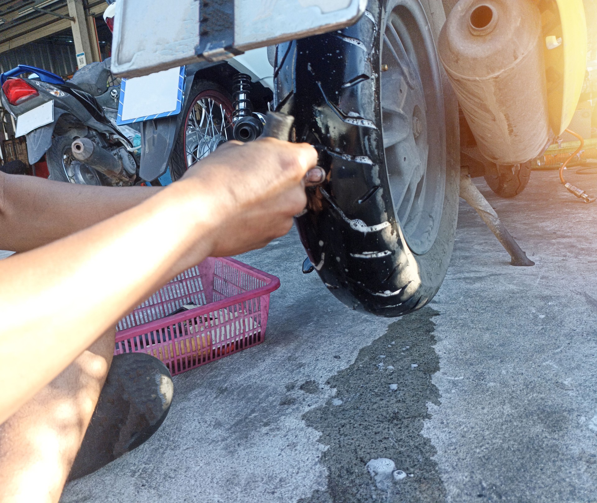 A motorcycle mechanic is patching a puncture in a tire.